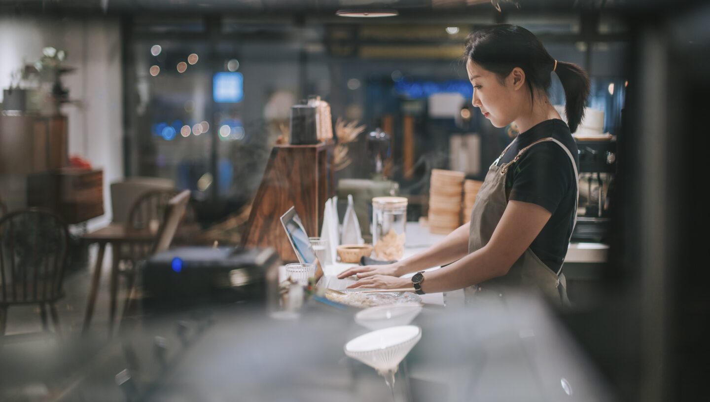 Small business owner managing finances and a café, representing cash flow planning for seasonal businesses.
